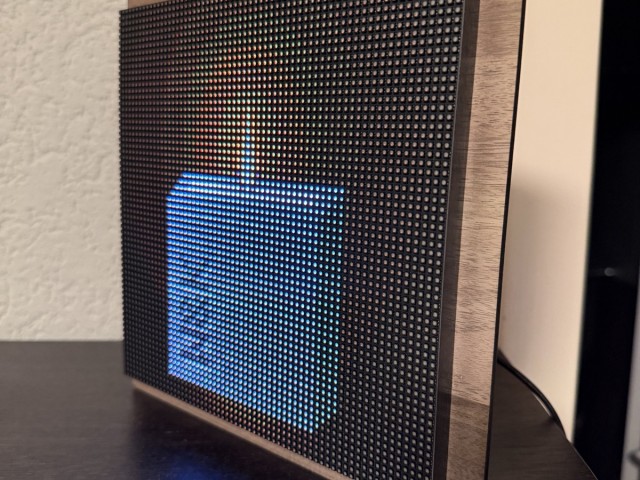 La Lucarne allumée sur un meuble, sa lumière bleue reflétée sur le bois